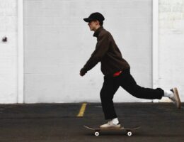 man in black pants and brown jacket riding skateboard