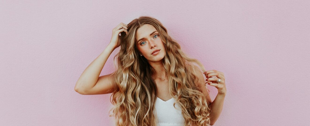 woman standing next to pink wall while scratching her head