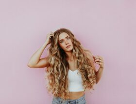 woman standing next to pink wall while scratching her head