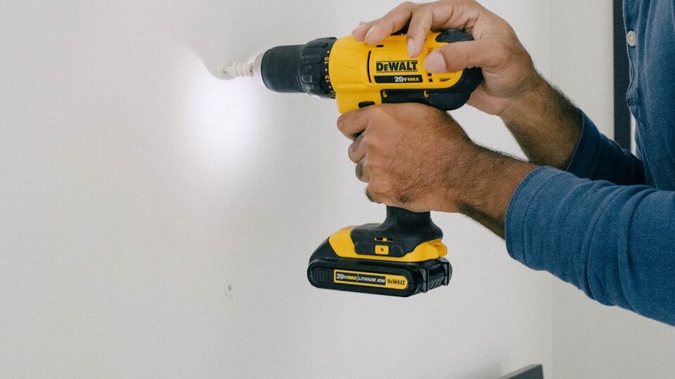 person holding yellow and black cordless hand drill