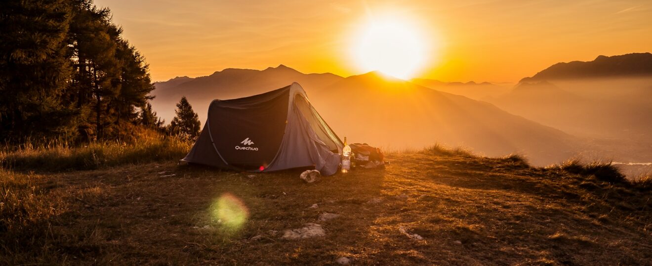 dome tent on mountain top with sun as background photo