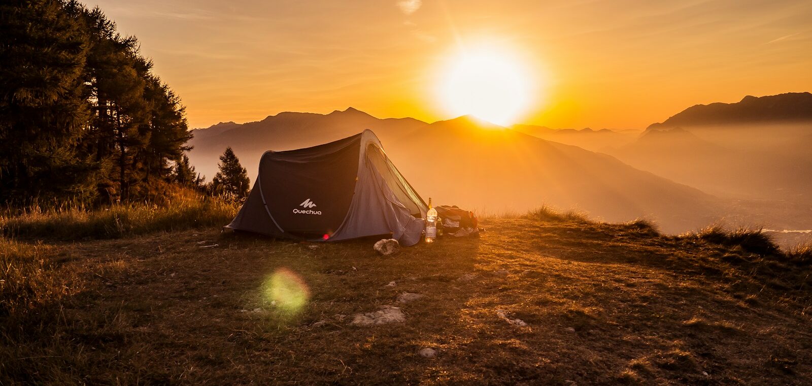 dome tent on mountain top with sun as background photo