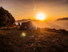 dome tent on mountain top with sun as background photo