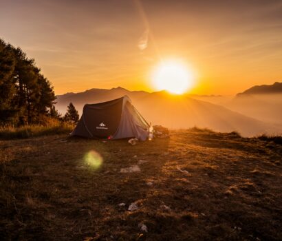 dome tent on mountain top with sun as background photo