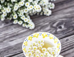 white and yellow cup with flowers on table