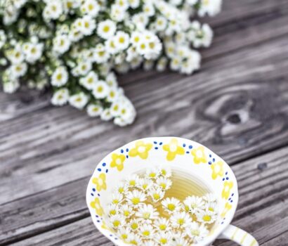 white and yellow cup with flowers on table