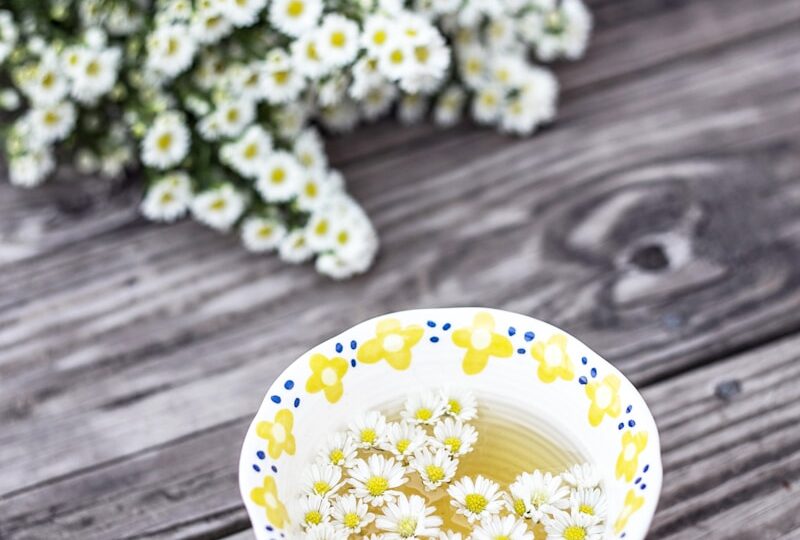 white and yellow cup with flowers on table