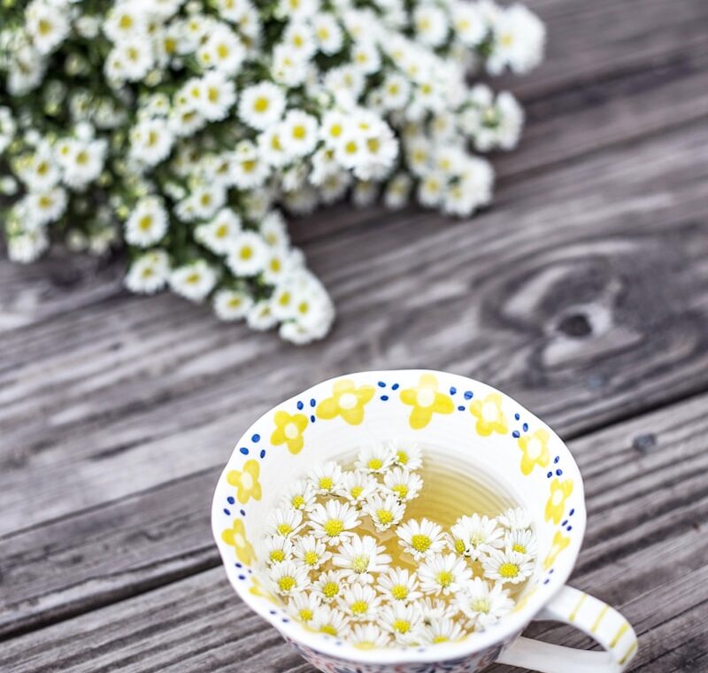 white and yellow cup with flowers on table